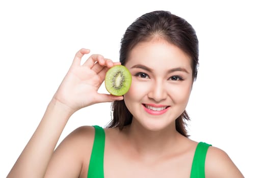 Tropical fruits. Healthy eating. Charming young asian woman holding fresh juicy kiwi and smiles. Green background.