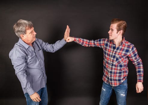 father and son lean on back to back isolated on black