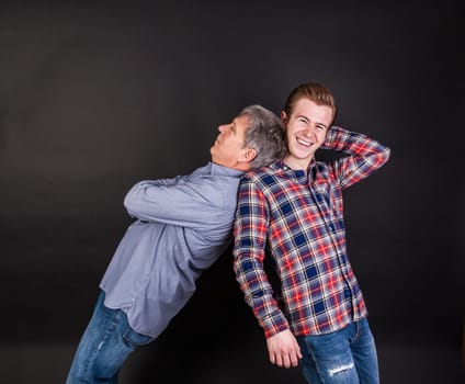 father and son lean on back to back isolated on black