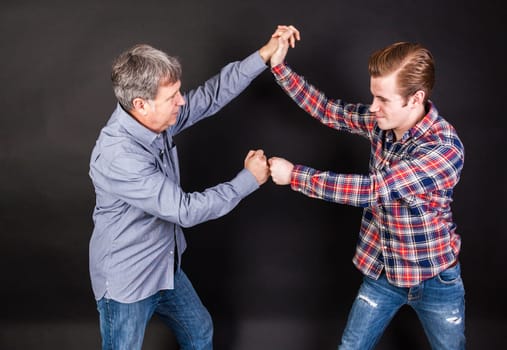 father and son lean on back to back isolated on black