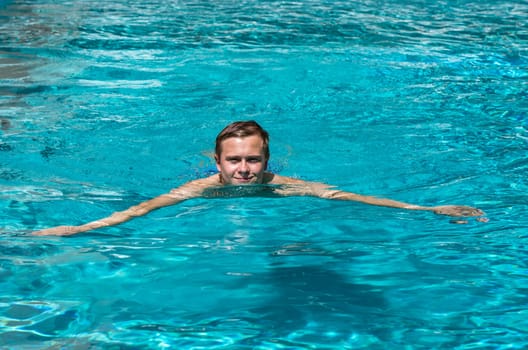 boy enjoys swimming in the outdoor swimming pool