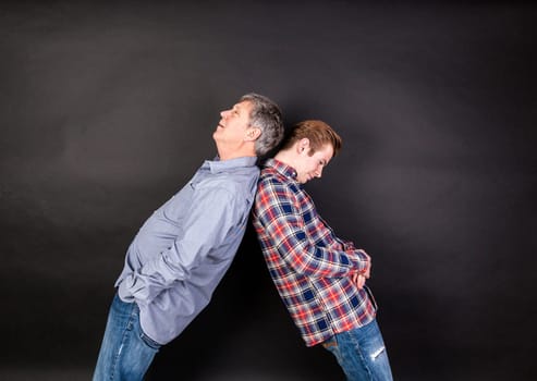 father and son lean on back to back isolated on black