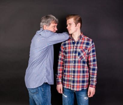 father and son lean on back to back isolated on black