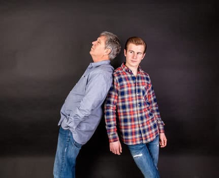 father and son lean on back to back isolated on black