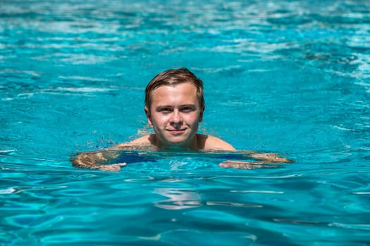 boy enjoys swimming in the outdoor swimming pool