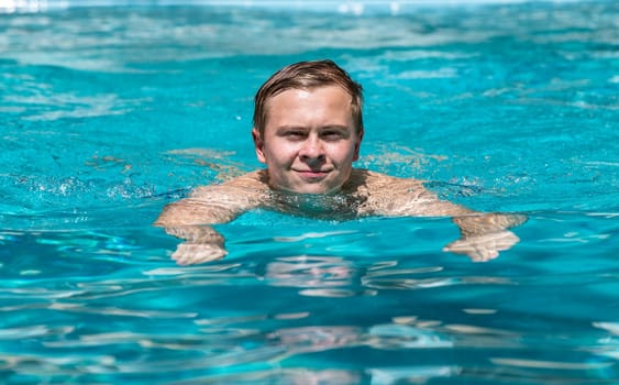 boy enjoys swimming in the outdoor swimming pool