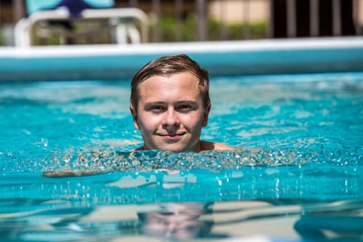 boy enjoys swimming in the outdoor swimming pool