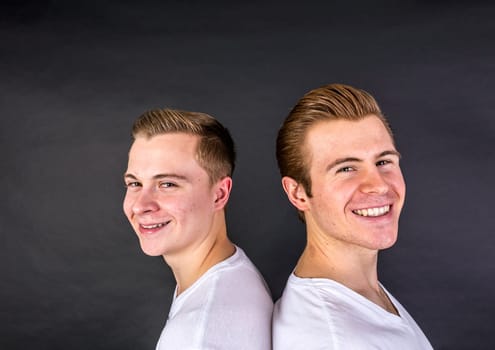 two teenage brothers standing back to back and have fun