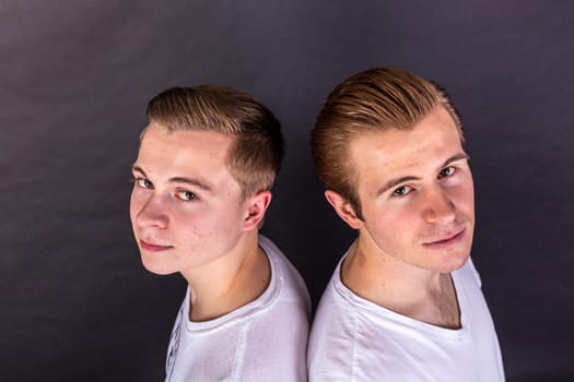 two teenage brothers standing back to back and have fun
