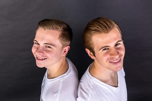 two teenage brothers standing back to back and have fun
