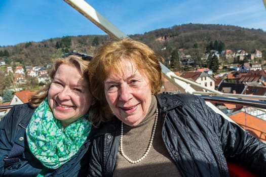 mother and daughter have fun at the ferris wheel under blue sky