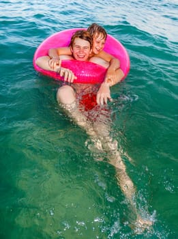 two brothers in a swim ring have fun in the ocean