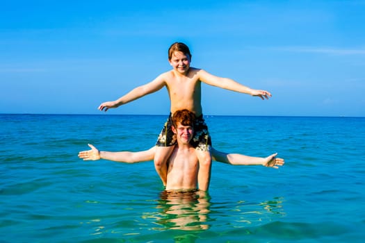 boys having fun playing Piggyback in the ocean