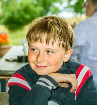 cute boy smiles and has fun sitting at the table