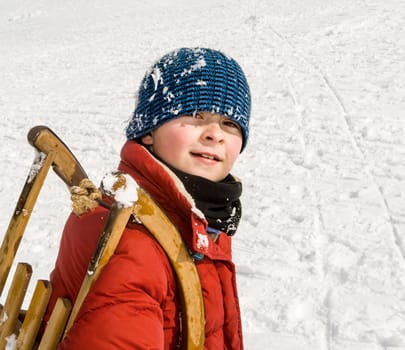 boy carries his sledge up the hill in winter