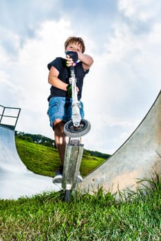 boy enjoys riding his scooter in the skate park