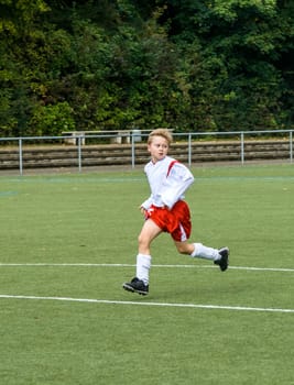 young soccer player runs over the green football ground