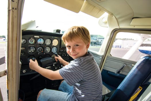 child has fun sitting in an aircraft at the pilots seat