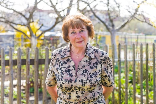 happy elderly woman is standing proud in her garden and smiles