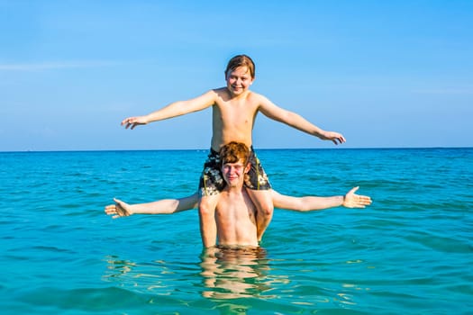 boys having fun playing Piggyback in the ocean