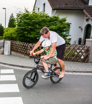 father and son are riding on one BMX, having fun and  enjoying it