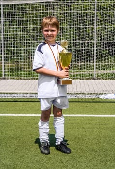 child keeps proudly the cup in its hand after the match