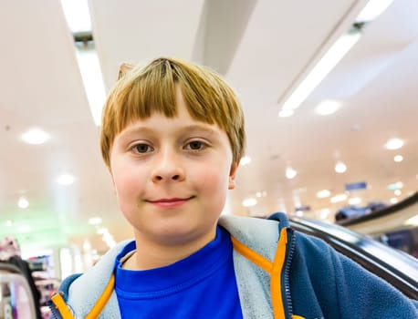 child on moving staircase looks self confident and smiles