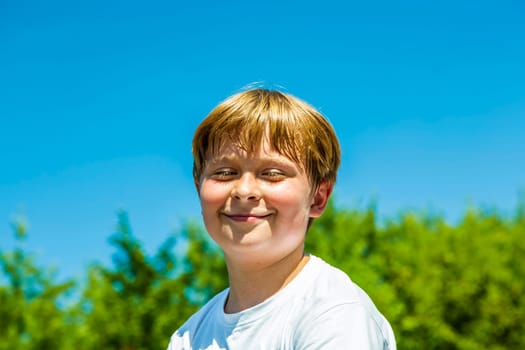 happy boy is smiling and closes eyes  under blue sky