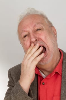 Yawning senior on a bright background