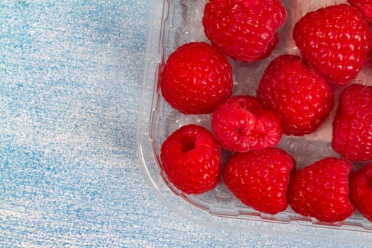 Fresh raspberries on a light blue background
