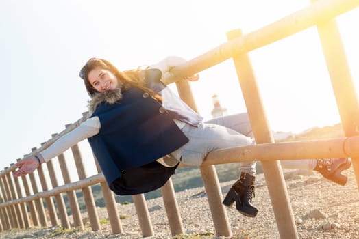 Beautiful happy young girl posing outdoors at sunset near a lighthouse