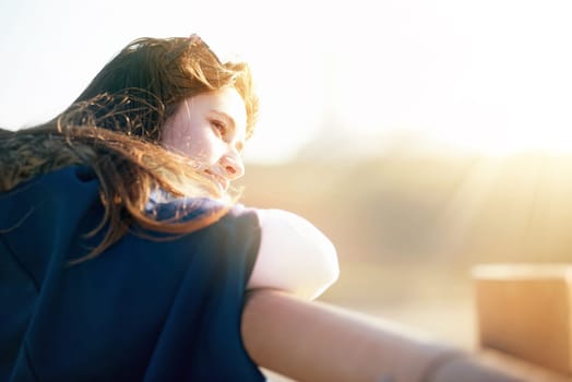 Beautiful happy young girl posing outdoors at sunset near a lighthouse