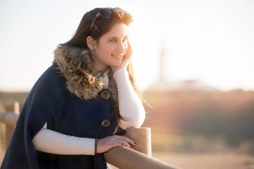 Beautiful happy young girl posing outdoors at sunset near a lighthouse