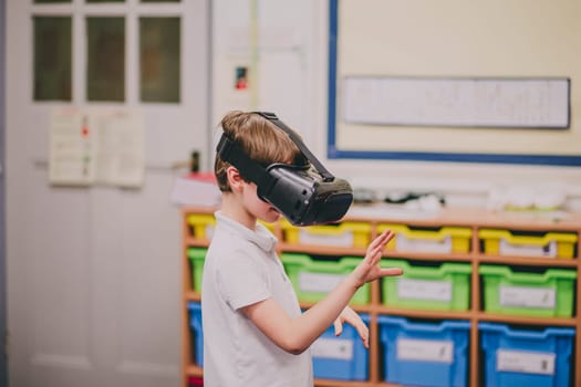 Little boy is experimenting with virtual reality in the classroom at school.