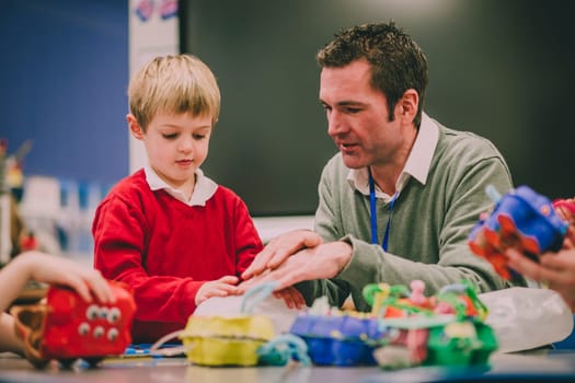 Teacher is helping his primary school student in the classroom with their STEM project.