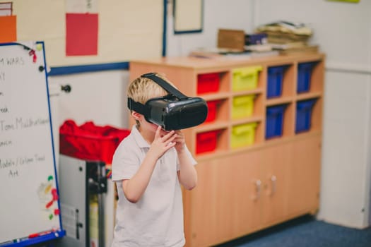 Little boy is experimenting with virtual reality in the classroom at school.