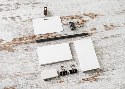 Blank branding template on vintage wooden table background. Bank business cards, pencil, eraser, badge and sharpener. Mock-up for your design. Responsive design mockup.