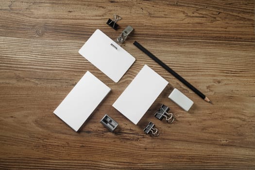 Photo of blank corporate identity. Stationery set on wooden table background. Branding mockup. Bank business cards, pencil, eraser, badge and sharpener. Top view.
