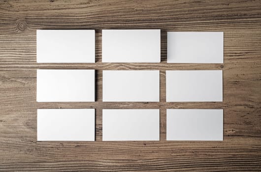 Many blank business cards on wood table background. Blank paperwork template for placing your design. Mockup for ID. Top view.