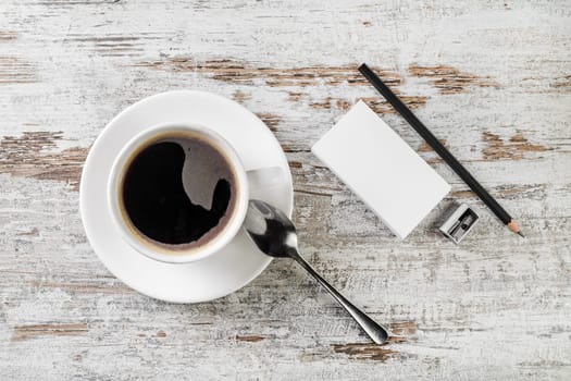 Still life with coffee. Coffee cup, bank business cards, spoon, pencil and sharpener on wooden table background. Top view.