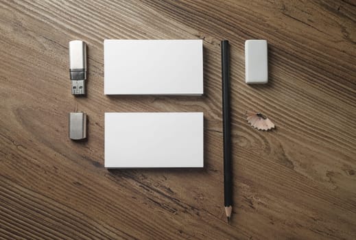 Blank paperwork template. Photo of blank stationery set. Mock-up for branding identity. Business cards, pencil, eraser and flash drive on wood table background. Top view.