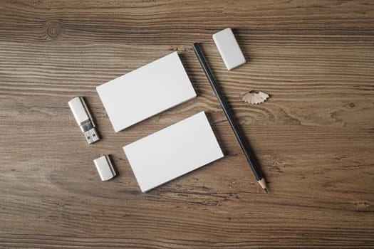 Blank stationery set on wooden table background. Bank business cards, pencil, eraser and flash drive. Mockup for branding identity for designers. Top view.