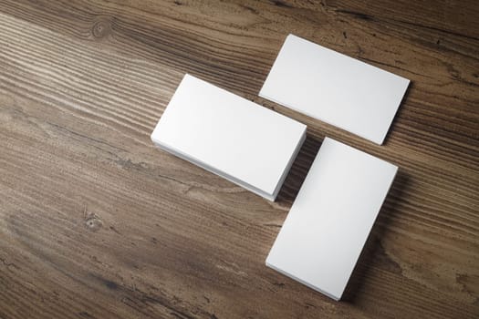 Photo of blank business cards on wooden office table background. Presentation template for branding identity. Top view.