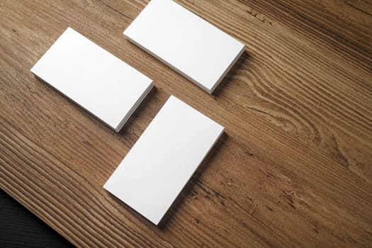 Piles of blank business cards on wood table background. Blank stationery. Mock up for branding identity for placing your design. Top view.