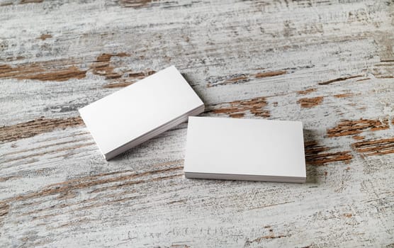Mockup of two piles of blank horizontal business cards at wooden table background.