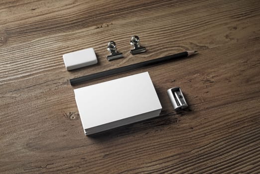 Blank stationery and corporate identity template. Photo of business cards, pencil, eraser and sharpener on wooden background.