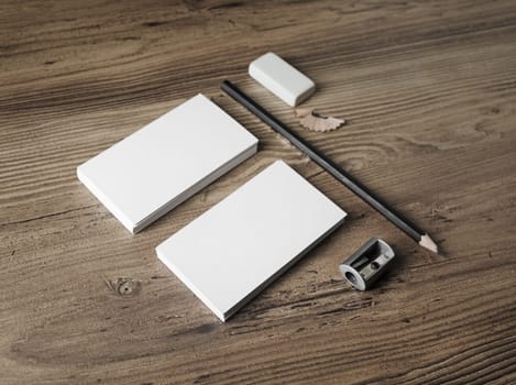 Blank stationery and corporate identity template. For design presentations and portfolios. Bank business cards, pencil, eraser and sharpener on wooden table background.