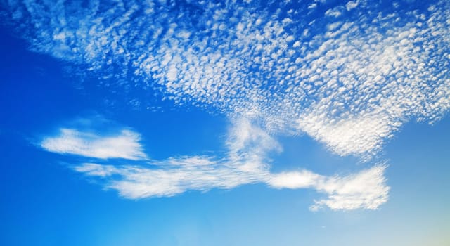 Blue sky with many fluffy scattered white clouds. Panoramic shot.