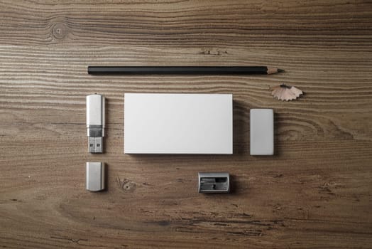Bank business cards, pencil, eraser, flash drive and sharpener on wood table background. Photo of blank stationery set. Mock up for branding identity. Top view.