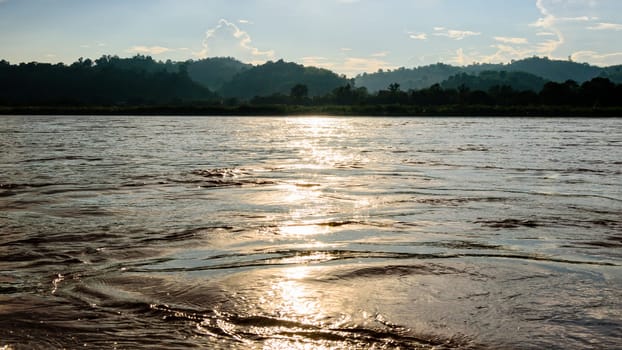 Beautiful natural landscape surface water of the Mekong River reflects golden sunlight during sunset in Thailand, 16:9 wide screen